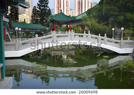 Chinese Water Garden Bridge and Reflection Amid Modern High Rise Buildings Wong Tai Sin Taoist Temple Kowloon Hong Kong