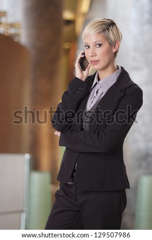 Trendy young woman in business suit talks on phone.