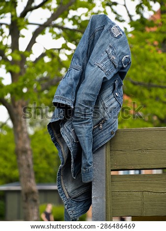 Blue jeans denim jacket hanged on a wooden fence