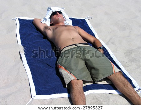 Young man sunbathing and relaxing on the beach