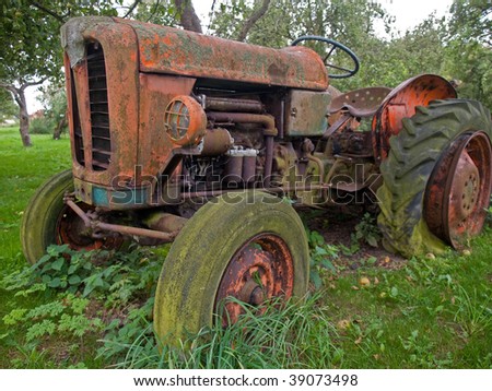 Old rusty red vintage tractor in a farm