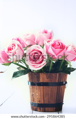pink roses in small wooden bucket