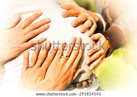 Hands on a pregnant woman\'s belly meaning they are going to help the mother with the raising of the baby