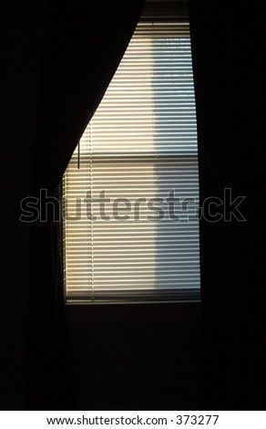 Shadowed window with a curtain on one side.