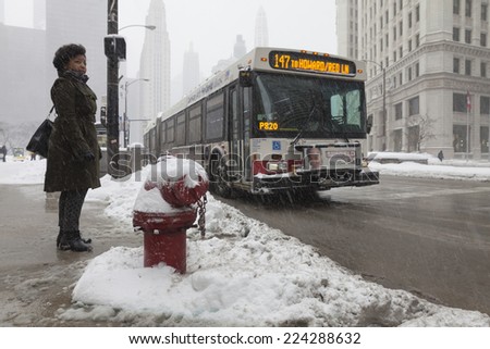 CHICAGO - FEBRUARY 4: A woman waits for the bus in Michigan Ave. in winter on February 4, 2014 in Chicago, IL.The winter of 2014 will be recorded as one of the harshest winters in the midwest.