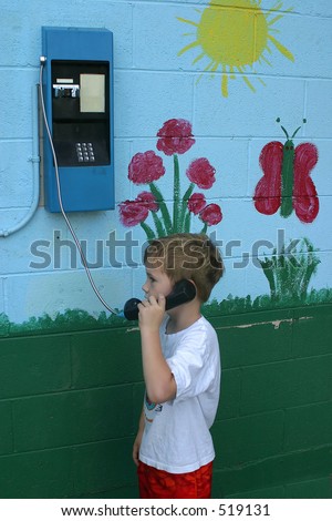 A little boy talking on a pay phone.