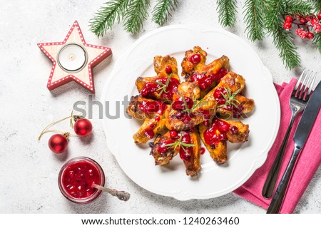 Baked chicken wings in cranberry sauce. Christmas dish with christmas decorations top view.