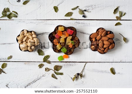 Almonds, cashews,  raisins and colored pineapple in a cookie cutters. On a white background with leaves of blueberry around