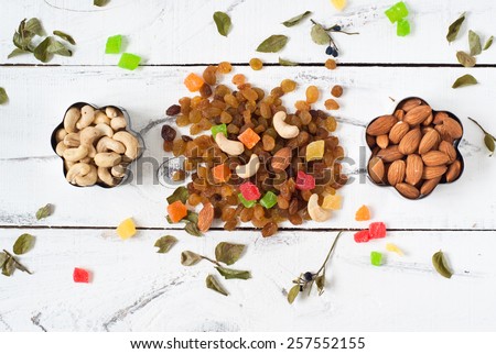 Almonds, cashews,  raisins and colored pineapple in a cookie cutters. On a white background with leaves of blueberry around