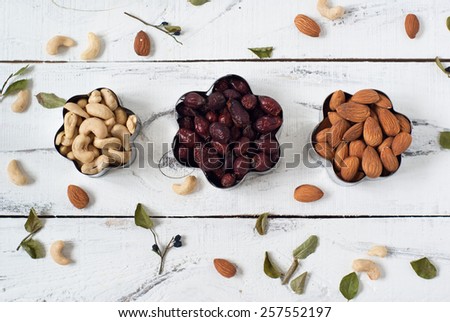 Almonds, cashews,  and dog rose in a cookie cutters. On a white background with leaves of blueberry around