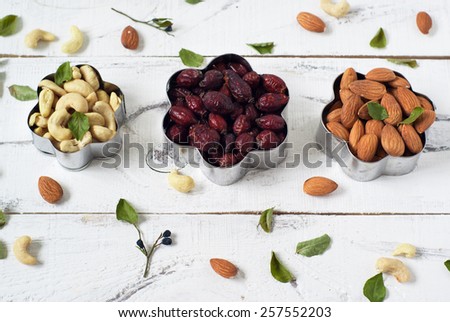 Almonds, cashews,  and dog rose in a cookie cutters. On a white background with leaves of blueberry around