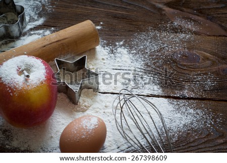 Ingredients for cooking baking - flour, egg, cookie cutters on wooden table. Image tinting.