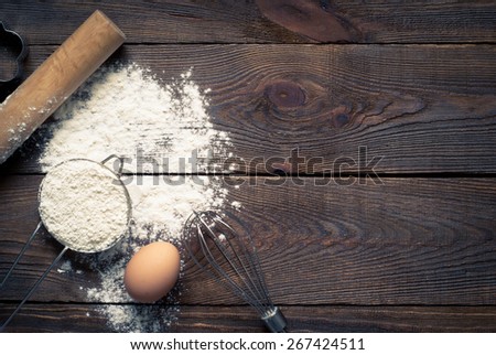 Ingredients for cooking baking - flour, egg, cookie cutters on wooden table. Image tinting.