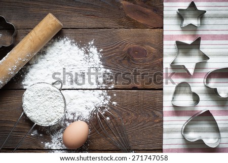 Ingredients for cooking baking - flour, egg, cookie cutters on wooden table