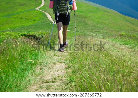 Hiking in the mountains. Hiker goes on the trail in the mountains