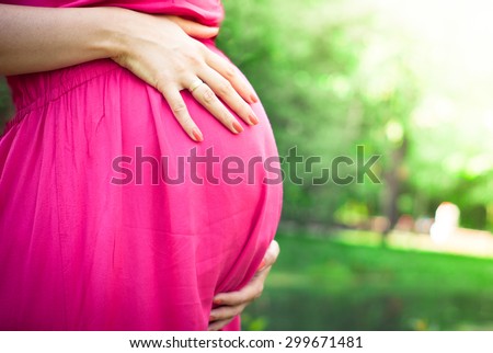 Pregnant woman in a pink dress outdoors