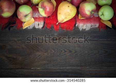 Autumn harvest. Apples and pears with yellow leaves on a wooden table.