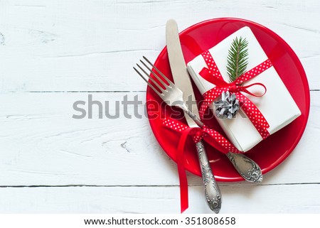 Christmas table setting with gift at white table. Top view, copyspace.