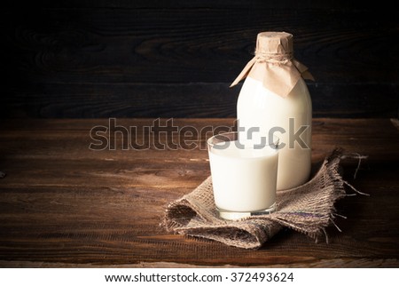 Old fashioned Bottle with milk and glass of milk at wooden table. Style rustic.