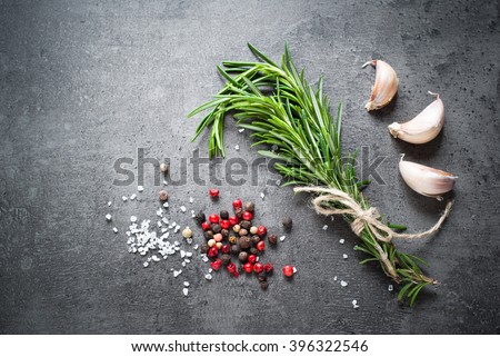 Black food background with olive oil, rosemary and spices, copy space, top view.