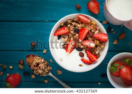 Granola. Granola with yogurt, honey and berries on blue wooden table.