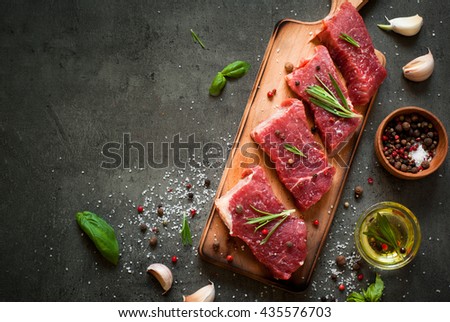 Raw meat. Raw beef steak on a cutting board with rosemary and spices.