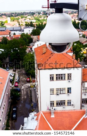 High tech overhead security camera at a tall building oversees City area./Surveillance camera