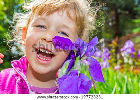 Young girl enjoying to play with a <b>Iris flower</b> - stock-photo-young-girl-enjoying-to-play-with-a-iris-flower-197723231