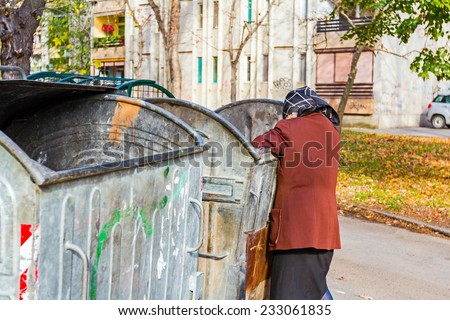 Homeless woman is searching for food in garbage dumpster/Woman in poverty/Woman is searching something in container