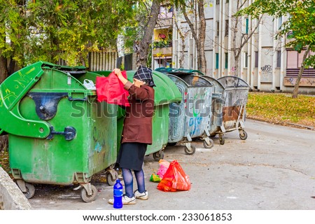 Homeless woman is searching for food in garbage dumpster/Woman in poverty/Woman is searching something in container