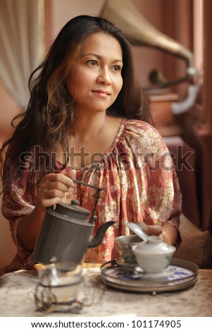 nostalgic woman  pouring tea in cup in retro interior