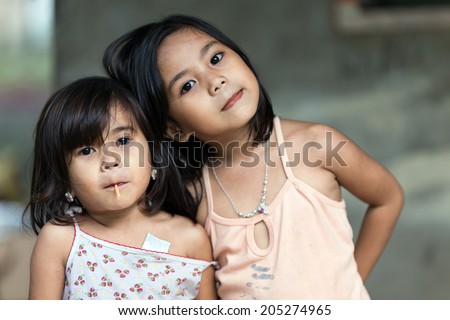 SIQUIJOR ISLAND, PHILIPPINES, DECEMBER 21, 2013: Two unidentified Filipino little girl sisters posing in front of her home in north Siquijor island, Philippines.