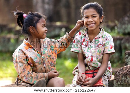 SIEM REAP, CAMBODIA, DECEMBER 04, 2012 : Little girl pinching the ear of her friend near the Beng Melea Khmer temple, Siem reap, Cambodia