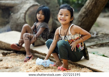 ANGKOR WAT, CAMBODIA, DECEMBER 06, 2012: Two Cambodian little girls are sitting near the temple for selling some souvenirs to tourists in Angkor wat, Siem Riep, Cambodia