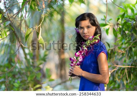 Close up Pretty Asian Woman in Blue Dress Holding Fresh Purple Flower While Looking at the Camera.