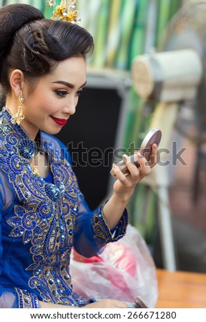 BANGKOK, THAILAND, February 17, 2015: A Thai lady dancer is checking her makeup make up on a mirror before the show at the Krung Kasem floating market in the Thewet district of Bangkok, Thailand