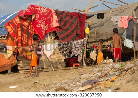 MANDALAY,MYANMAR,JANUARY 17, 2015 : Some kids are standing near a slum house in a very poor and dirty area near the river in Mandalay, Myanmar (Burma).