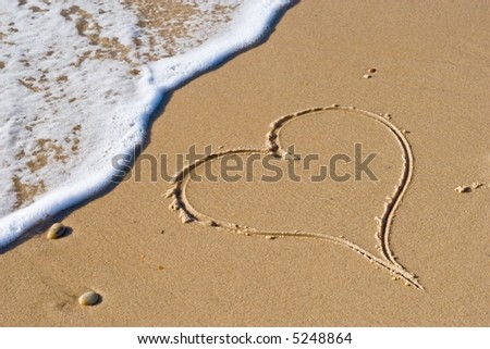 handwritten heart on sand with wave approaching