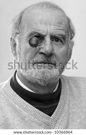 black and white portrait of a funny senior man with bottle cap in an eye