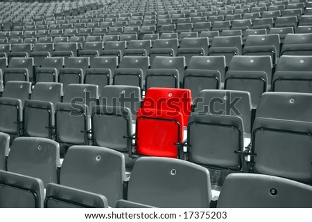 black and white picture of stadium seat with only one red