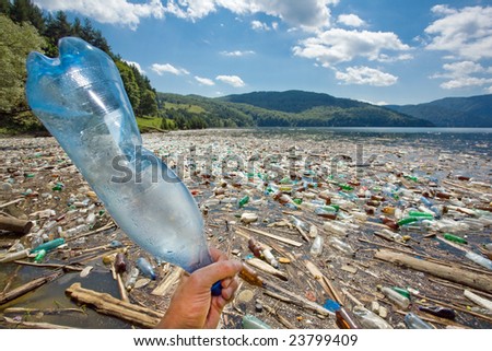 hand throwing plastic bottle in beautiful landscape ruined by pollution, bicaz lake, romania