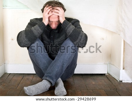 sad man seated on the floor at home