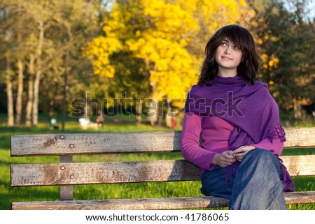 happy woman beauty seated on park bench in autumn