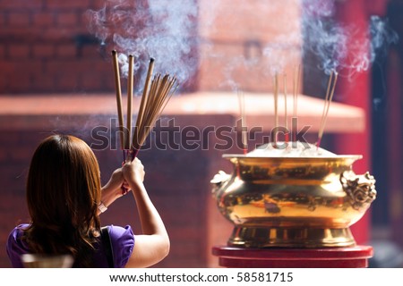 woman holding smoking big incense sticks in chinese temple, Kuala Lumpur, malaysia