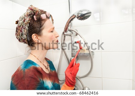 funny woman cleaning bathroom shower with brush