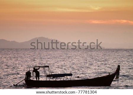 fisherman and boat silhouette at sunset, thailand