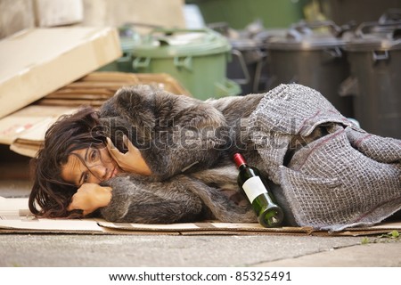 poor woman tramp lying among bin with wine bottle