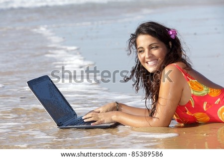 young woman using laptop in sea water at beach