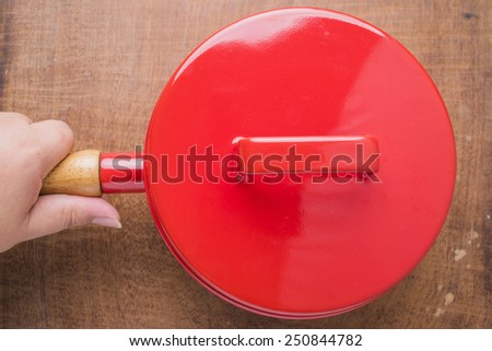 Red cooking pot vintage kitchen utensils on a wooden background.