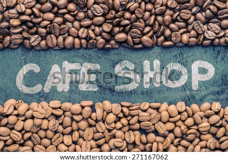 Coffee beans with Cafe Shop hand writing on black wooden background with blank space. Photo in vintage color tone style.